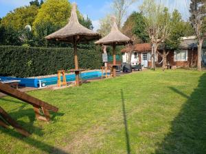 a yard with two picnic tables and umbrellas at Quinta El Cholito in Luján