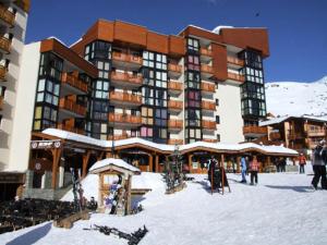 Un grand bâtiment dans la neige avec des gens debout à l'extérieur dans l'établissement Résidence Eskival - ESKIVAL APPARTEMENT 35M² 4 PERS CENTRE STATION ACCES DIRECT SUR LES PISTES MAE-7711, à Val Thorens