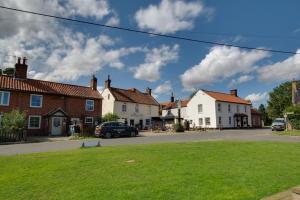 a row of houses on a street with a green lawn at Ivy Cottage in Thurgarton