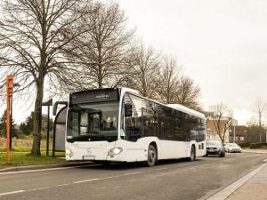 a white bus is driving down a street at Novotel Brussels Airport in Diegem