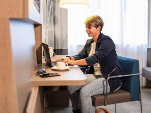 a woman sitting at a table with a computer at Novotel Brussels Airport in Diegem
