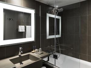 a bathroom with a sink and a tub and a mirror at Novotel Brussels Airport in Diegem +192 photos