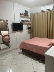 a bedroom with a bed and a tv and a mirror at Prédio 320 São Brás in Belém