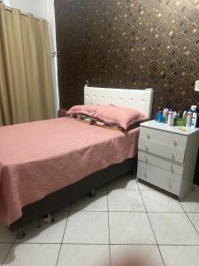 a bedroom with a bed with pink sheets and a dresser at Prédio 320 São Brás in Belém