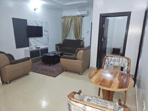 a living room with a table and chairs and a tv at BELTIJ luxury Apartment in Ilesa