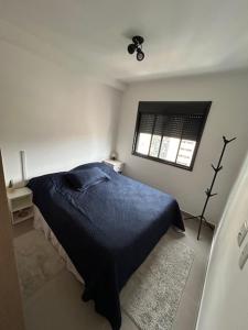 ein Schlafzimmer mit einem blauen Bett und einem Fenster in der Unterkunft Apto novo e aconchegante ao lado do Allianz in São Paulo