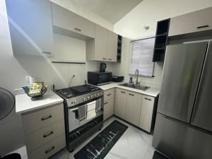 a small kitchen with a stove and a refrigerator at Zae's Retreat 2 bed 1 Bath in Portmore Jamaica in Newlands +15 photos