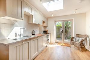 a kitchen with white cabinets and a sink at Point Cottage in Blakeney