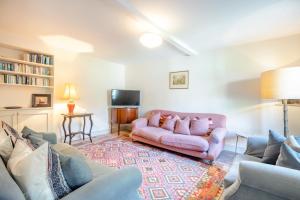 a living room with a pink couch and a tv at Point Cottage in Blakeney