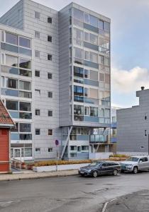 a large building with cars parked in front of it at ArticVieW Tromsø city centre in Tromsø