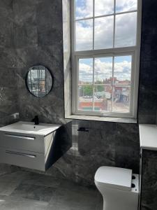 a bathroom with a sink and a window and a toilet at Stylish modern 2 bedroom flat 6B in Denton