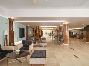 a lobby with chairs and tables in a building at Novotel Cairo Airport in Cairo