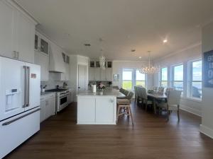 a white kitchen with a table and a dining room at Salty Sunset Bay breeze, golden skies, and coastal vibes in Mustang Beach