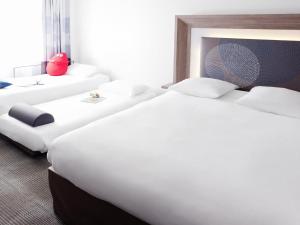 a hotel room with two large beds with white pillows at Novotel Nottingham Derby in Long Eaton
