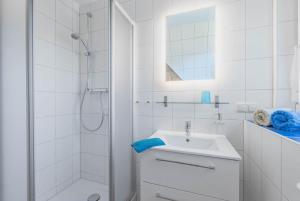 a white bathroom with a sink and a shower at Ferienwohnung Strand in Prerow
