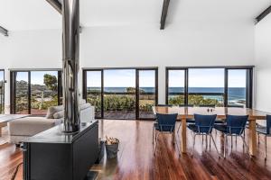 a living room with a table and chairs and the ocean at The C House at Skenes Creek in Skenes Creek