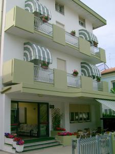 een groot wit gebouw met balkons, tafels en stoelen bij Hotel Carmen Viserba in Rimini