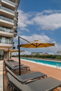 a row of lounge chairs with an umbrella and a pool at Stylish Luxury Apartment - Fully Equipped in Asuncion
