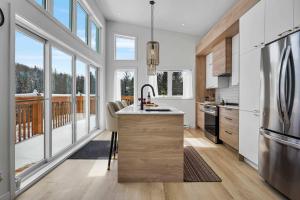a kitchen with white walls and windows and a kitchen island at Twin Cottages by the River - Corpo & Events in La Macaza