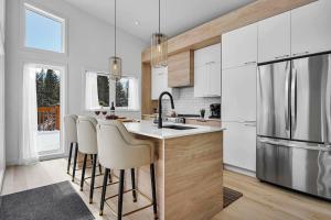 a kitchen with white cabinets and a kitchen island with bar stools at Twin Cottages by the River - Corpo & Events in La Macaza