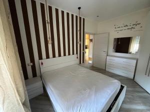 1 dormitorio con cama blanca y pared a rayas en La Concordia, en Novi Ligure