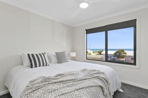 a white bedroom with a large bed and a window at Benswan at the bay - 5 bedrooms in Apollo Bay