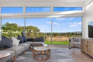 sala de estar con ventanas grandes y sofá en Cedar Tides - cedar hot tub, en Apollo Bay