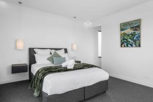 una camera da letto con un letto con lenzuola bianche e un dipinto di Sunrise Serenity - modern luxury a Apollo Bay