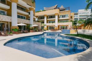 a swimming pool in front of a building at Pueblito luxury apartment in Playa del Carmen
