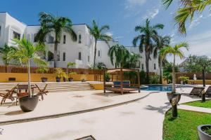a large white building with palm trees and a pool at Pueblito luxury apartment in Playa del Carmen