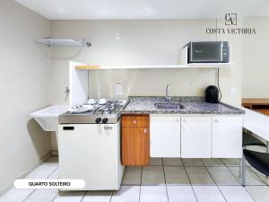 a small kitchen with a sink and a stove at Costa Victoria Residence in Vitória