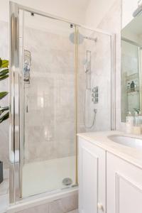 a white bathroom with a shower and a sink at Large Belgravia Georgian Mansion House in London