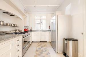 a kitchen with white cabinets and a stainless steel refrigerator at Large Belgravia Georgian Mansion House in London +25 photos