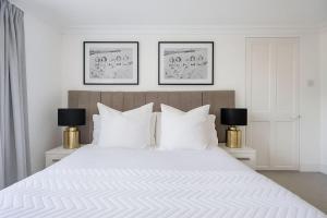a bedroom with a large white bed with two lamps at Large Belgravia Georgian Mansion House in London