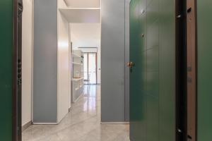 a hallway with green doors and a tile floor at La casetta in Castel Maggiore