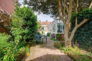 een tuin met een tafel en stoelen en een boom bij Garden Cottage in Holt