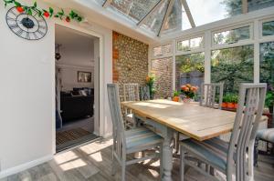 een eetkamer met een houten tafel en stoelen bij Garden Cottage in Holt