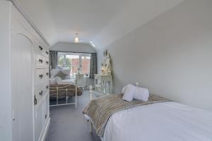 een witte slaapkamer met een bed en een stoel bij Garden Cottage in Holt