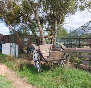 a wooden cart sitting in the grass next to a fence at Au refuge de Lahontan in Castelnau-dʼAuzan