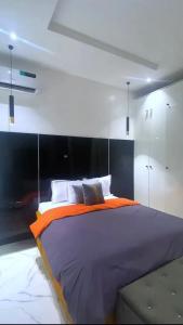 een slaapkamer met een groot bed en een oranje deken bij 3 bedroom apartment, Ikate in Lekki