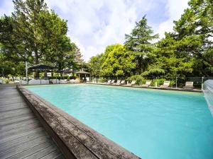 a large swimming pool with chairs and trees at Mercure Bordeaux Lac in Bordeaux