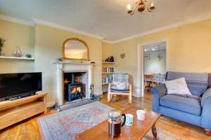 un soggiorno con un divano blu e un camino di Holly Cottage a Cromer
