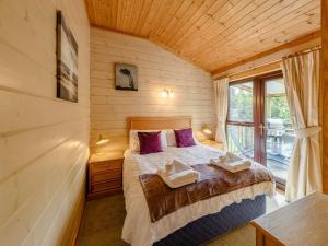 a bedroom with a bed with purple pillows and a window at 3 Bed in Clovelly 85290 in Woolfardisworthy