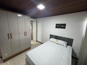 ein Schlafzimmer mit einem weißen Bett und einem Schrank in der Unterkunft Villa Hípica Resort Gravatá - Apartamento 701 in Gravatá + 9 Fotos