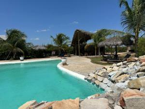 a swimming pool with a rock wall next to a resort at Chaleville Maramar in Luis Correia
