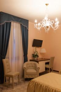a bedroom with a bed and a desk and a chandelier at B&B Palazzo Mantegna in Gioiosa Ionica