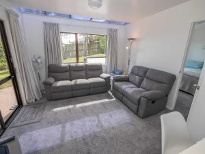 a living room with two couches and a window at The Garden Flat in Mangonui