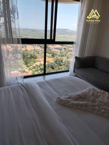 a bed in a room with a large window at Marina View Luxury Suites Munyonyo Kampala in Kampala