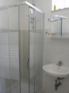 een badkamer met een glazen douche en een wastafel bij Apartments Senka in Žirje +23 foto's