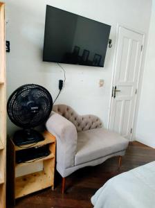 a room with a chair and a television on the wall at casa santos cop 30 in Belém